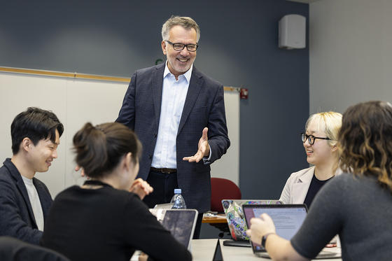 Dean Alpaslan Ozerdem talks with a table of students during class.